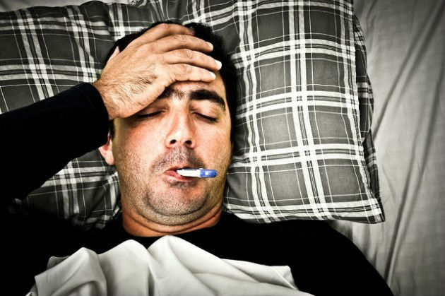a sick man in bed with a thermometer in his mouth