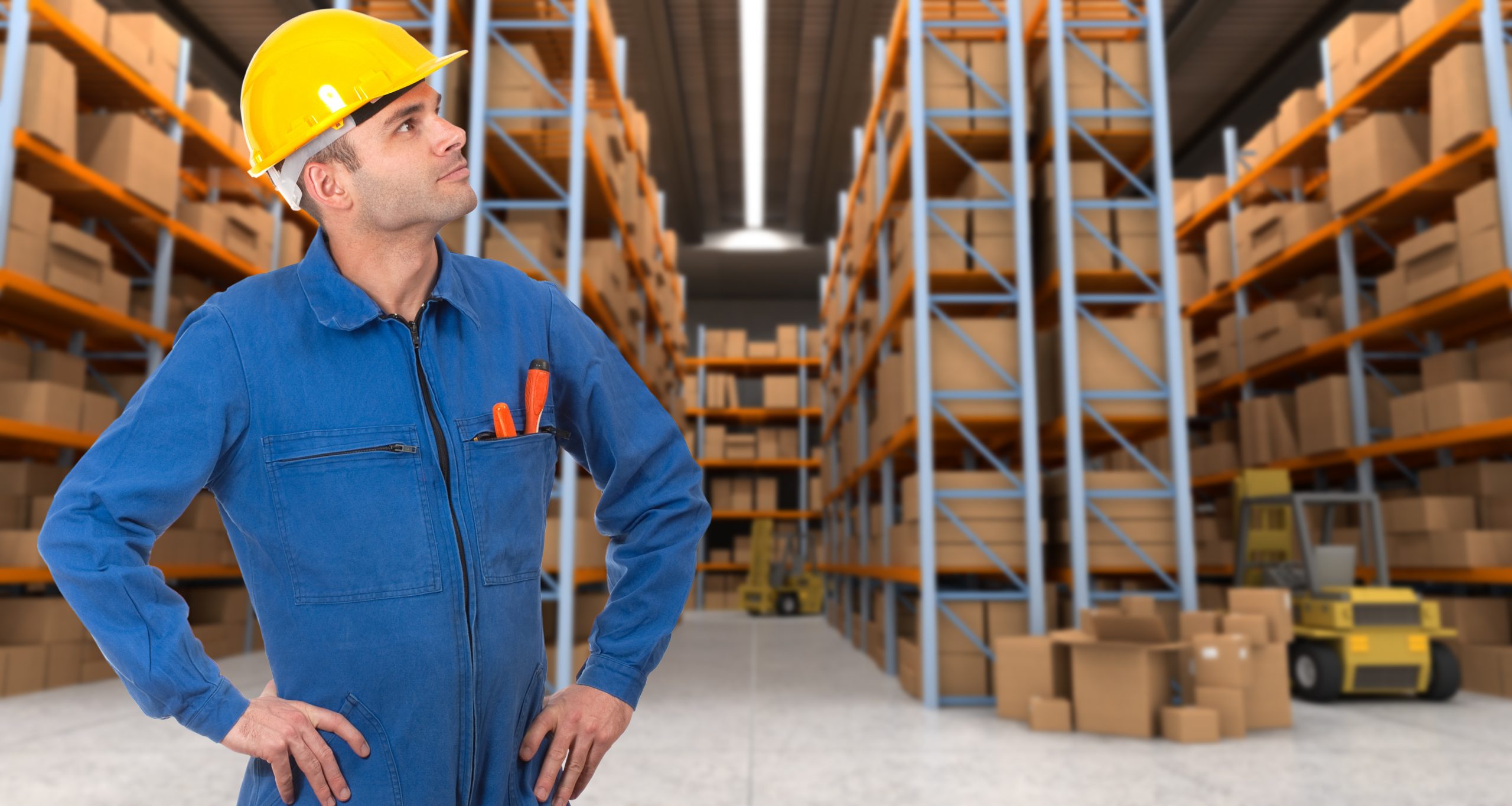 Man with helmet and blue overalls in a warehouse with pallet racking system